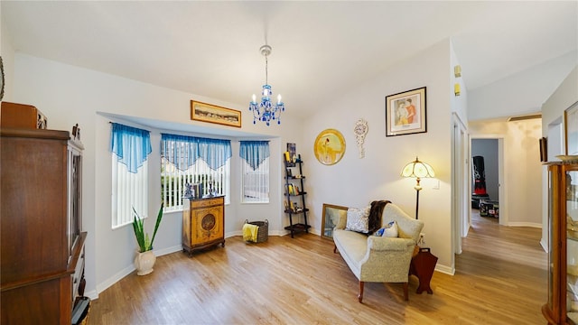 living area featuring light hardwood / wood-style flooring, vaulted ceiling, and a notable chandelier