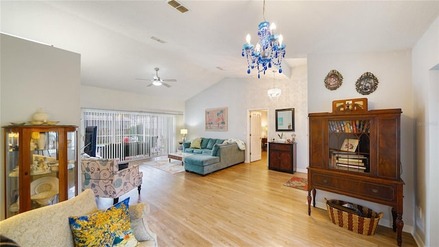 living room featuring ceiling fan with notable chandelier, light wood-type flooring, and lofted ceiling