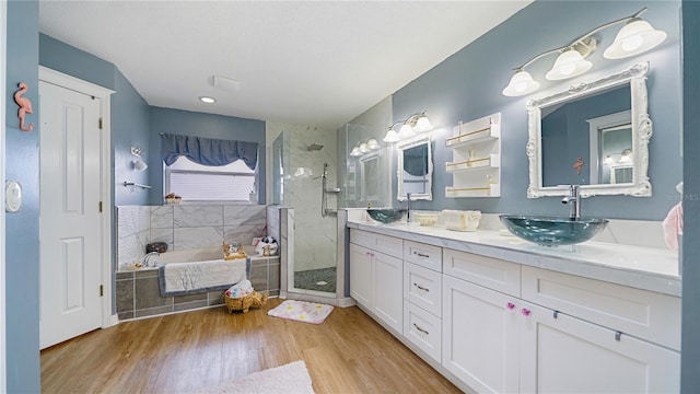 bathroom featuring hardwood / wood-style floors, vanity, and plus walk in shower