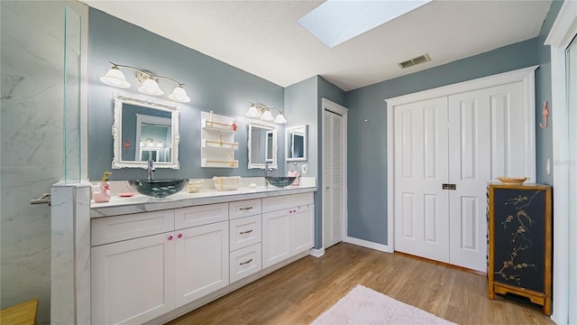 bathroom with vanity, a shower, a skylight, a textured ceiling, and wood-type flooring