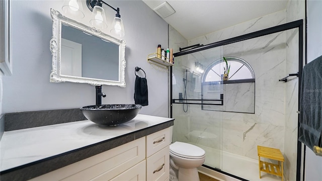 bathroom featuring a shower with door, vanity, and toilet