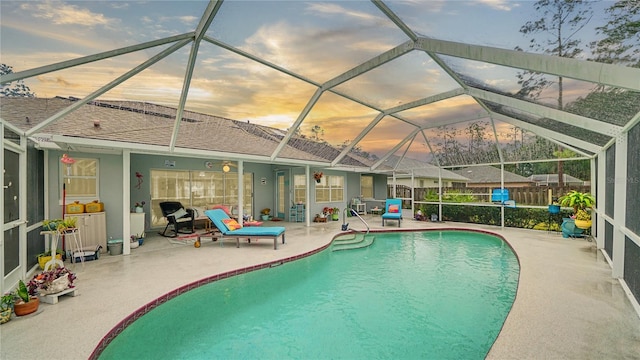 pool at dusk featuring glass enclosure and a patio area