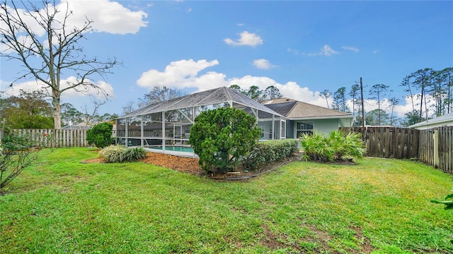 rear view of property with a lawn, a lanai, and a fenced in pool