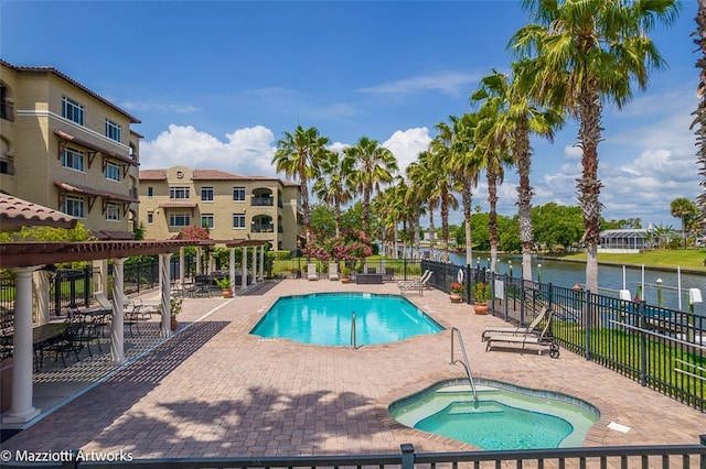 view of swimming pool featuring a patio area, a water view, and a hot tub