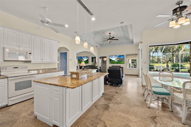 kitchen featuring a center island, white cabinets, decorative light fixtures, and white appliances