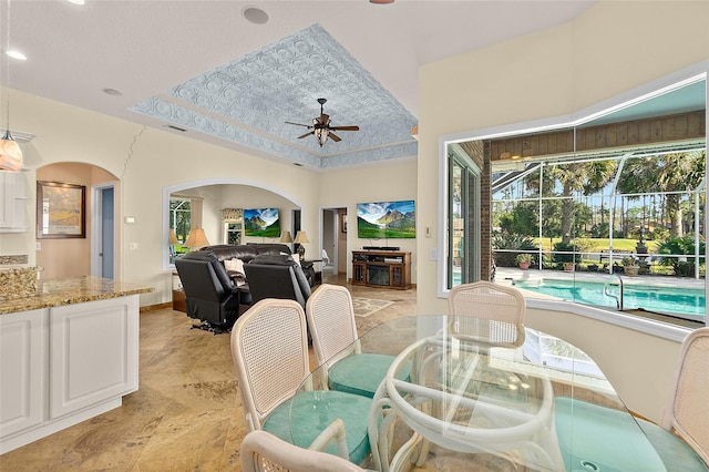 dining space featuring ceiling fan and a tray ceiling