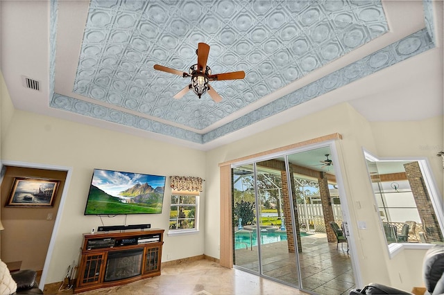 living room featuring a tray ceiling, ceiling fan, and a high ceiling