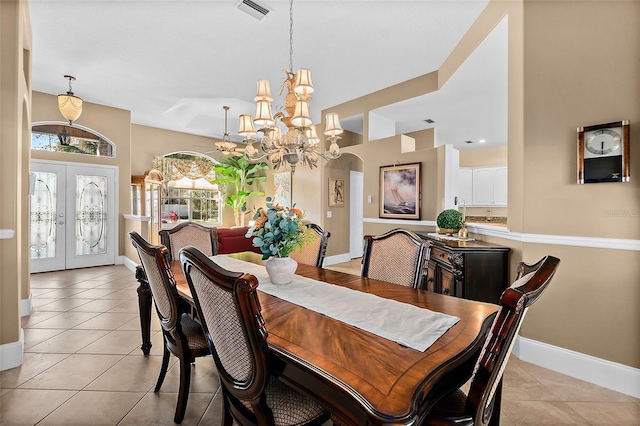 dining room with a notable chandelier, light tile patterned floors, and french doors