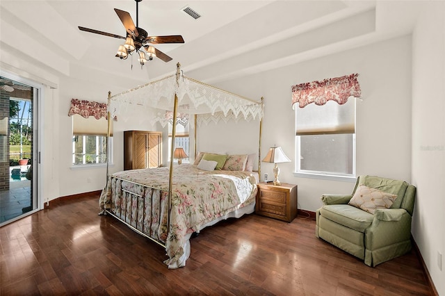 bedroom featuring access to exterior, dark hardwood / wood-style floors, a raised ceiling, and ceiling fan