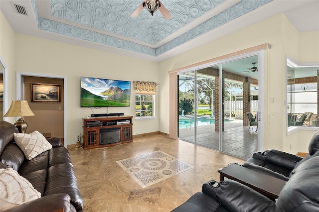 living room featuring a high ceiling, a raised ceiling, and ceiling fan