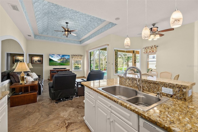 kitchen with a tray ceiling, white cabinetry, sink, and pendant lighting