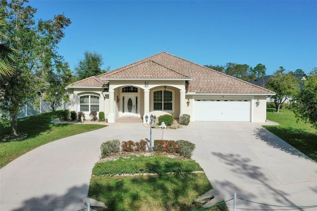 mediterranean / spanish home with a garage and a front lawn