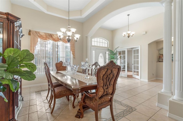 tiled dining space with decorative columns, a high ceiling, and an inviting chandelier