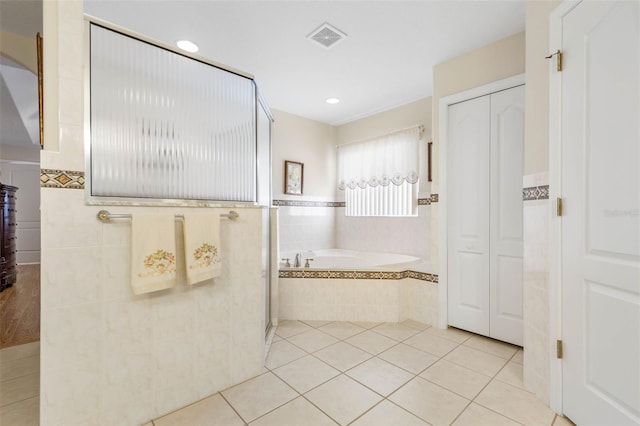 bathroom with separate shower and tub, tile patterned flooring, and tile walls