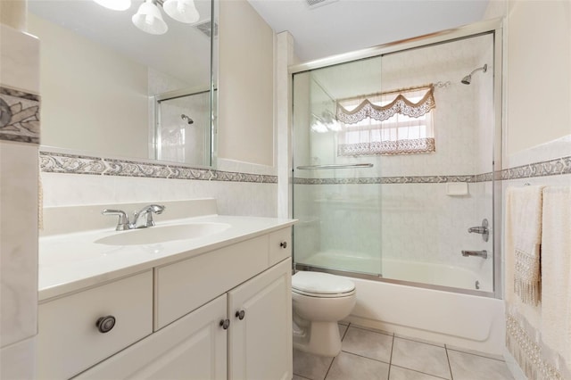 full bathroom with vanity, shower / bath combination with glass door, tile walls, tile patterned flooring, and toilet