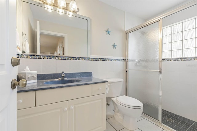 bathroom featuring walk in shower, tile patterned flooring, toilet, vanity, and tile walls