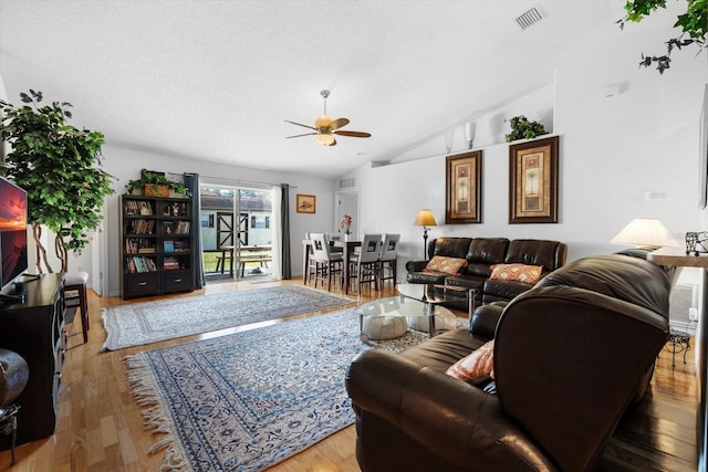 living room featuring a textured ceiling, ceiling fan, wood-type flooring, and lofted ceiling