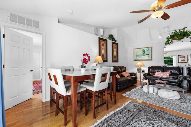 dining space with hardwood / wood-style floors, vaulted ceiling, and ceiling fan