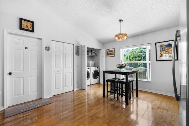 dining area featuring a textured ceiling, separate washer and dryer, vaulted ceiling, and hardwood / wood-style flooring