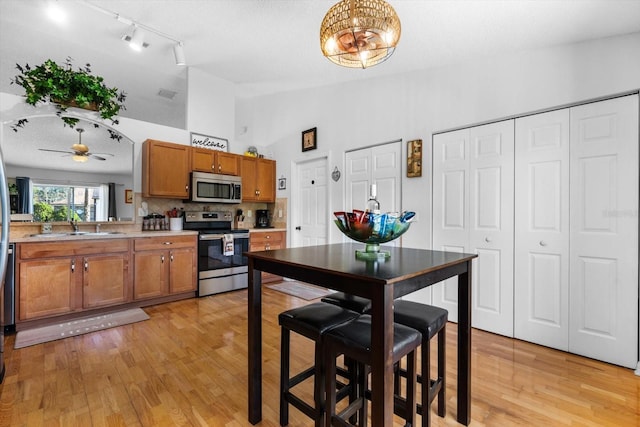 kitchen featuring appliances with stainless steel finishes, backsplash, vaulted ceiling, ceiling fan, and sink