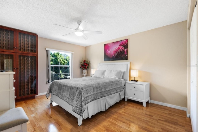 bedroom featuring ceiling fan, light hardwood / wood-style floors, and a textured ceiling