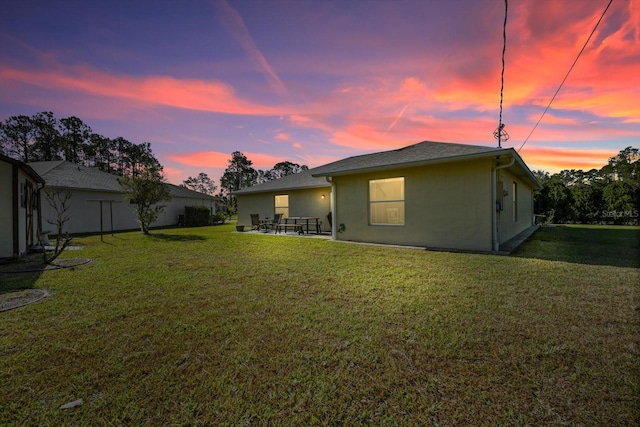 back house at dusk with a lawn