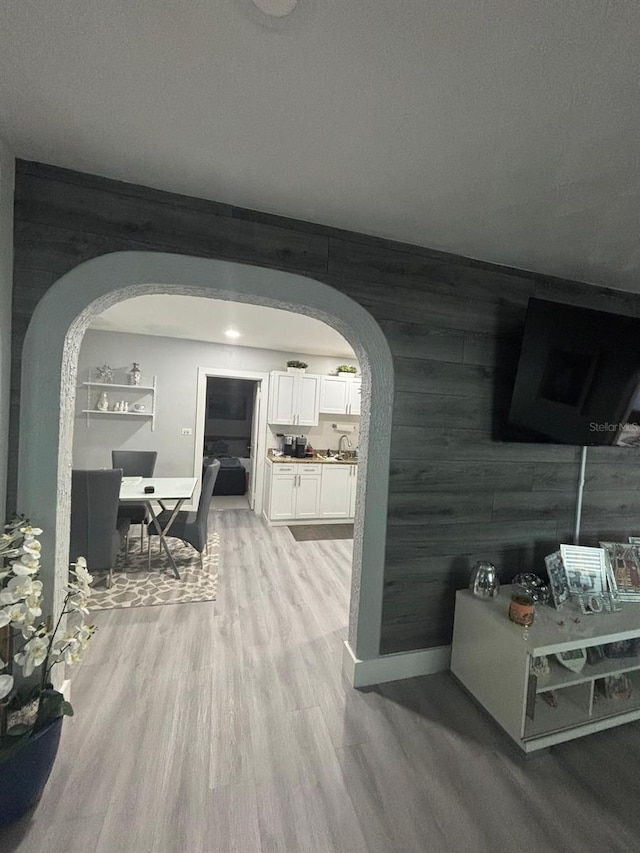 corridor featuring light wood-type flooring and wooden walls