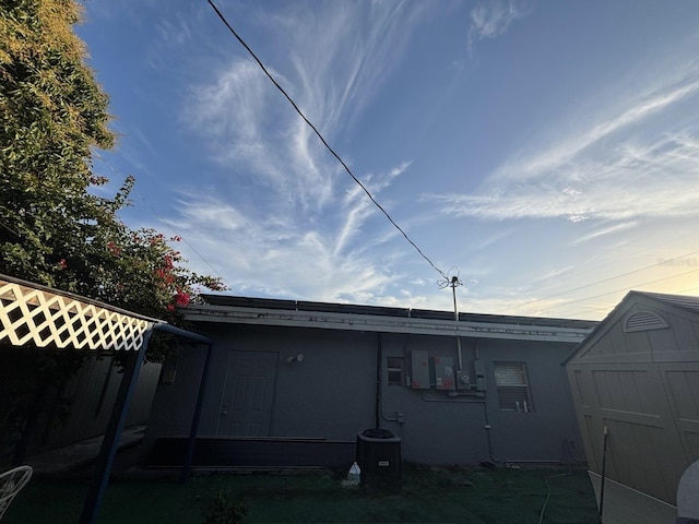 view of side of home featuring cooling unit and a shed