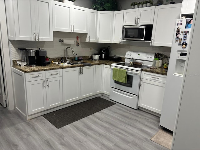 kitchen with dark stone countertops, white cabinetry, sink, and white appliances