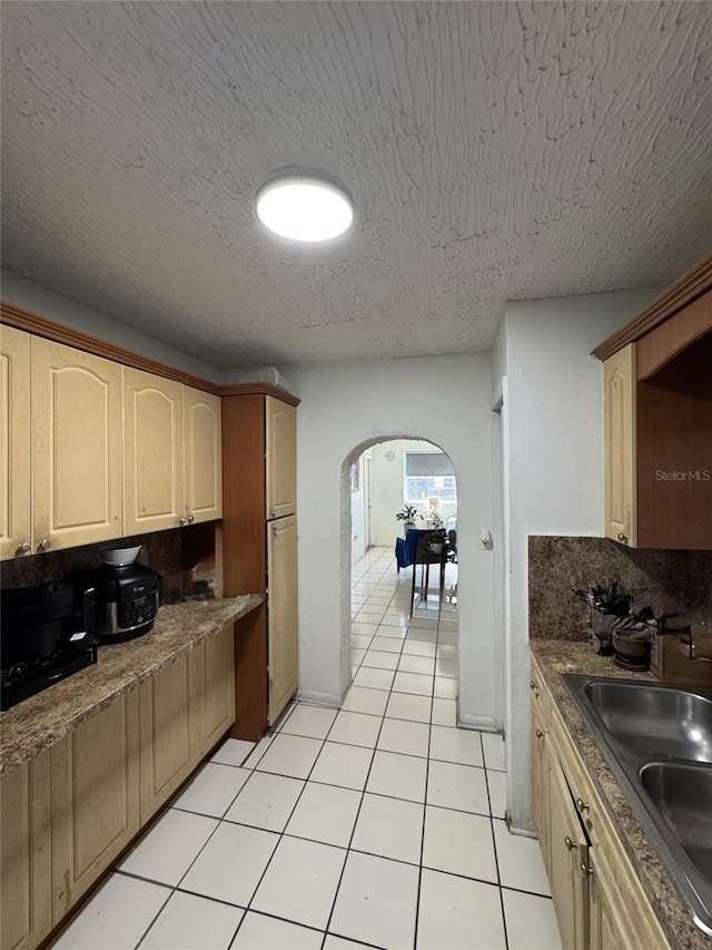 3565 NW 81st Ter, Miami, FL 33147 - kitchen with light tile patterned floors, arched walkways, a textured ceiling, light brown cabinetry, and a sink