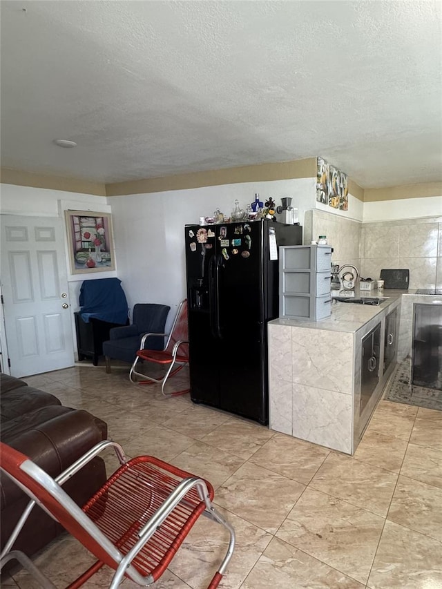 3565 NW 81st Ter, Miami, FL 33147 - kitchen with light countertops, black refrigerator with ice dispenser, a textured ceiling, and a sink