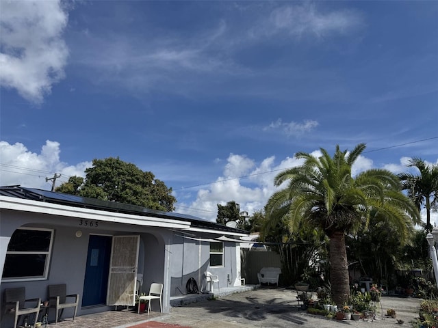 3565 NW 81st Ter, Miami, FL 33147 - view of front of house with roof mounted solar panels, fence, metal roof, and stucco siding