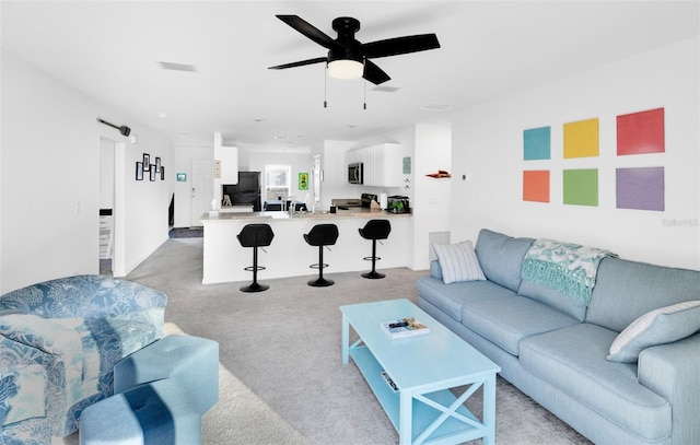 carpeted living room with ceiling fan