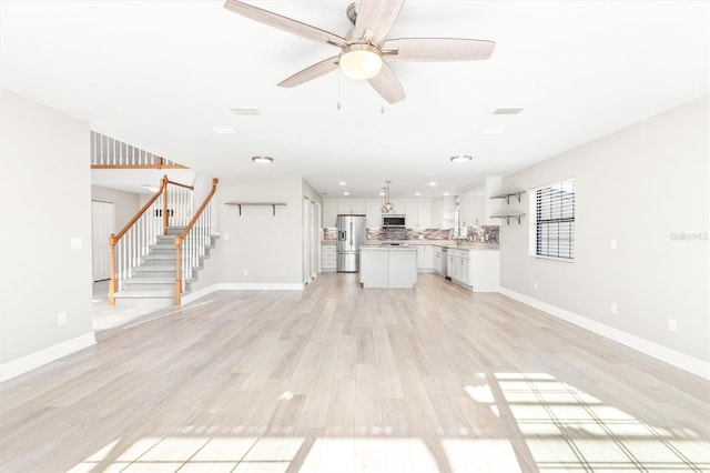 unfurnished living room featuring ceiling fan and light hardwood / wood-style floors