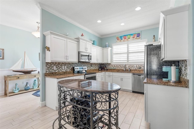 kitchen with sink, tasteful backsplash, appliances with stainless steel finishes, white cabinets, and ornamental molding