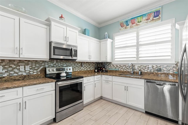 kitchen with sink, stainless steel appliances, tasteful backsplash, dark stone counters, and white cabinets