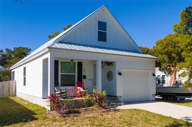 view of front of home with covered porch, a garage, and a front lawn