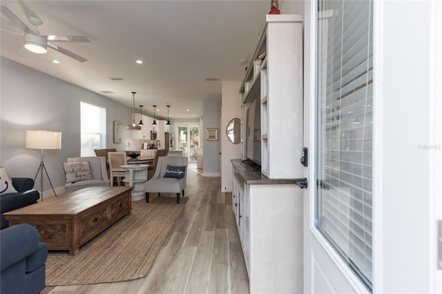 living room with light wood-type flooring and ceiling fan