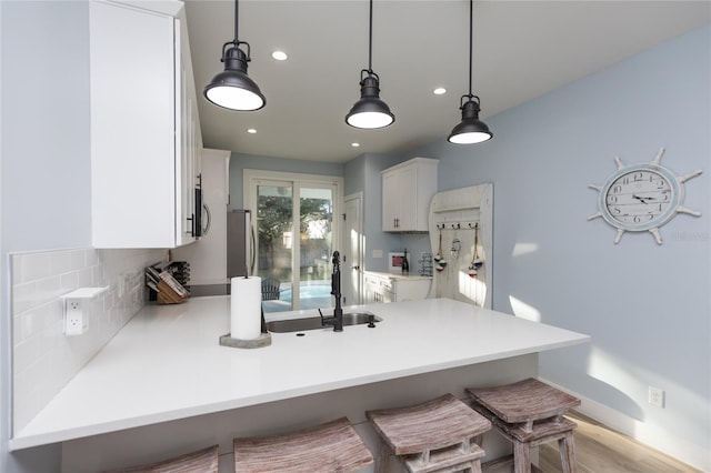 kitchen featuring kitchen peninsula, sink, white cabinets, and pendant lighting