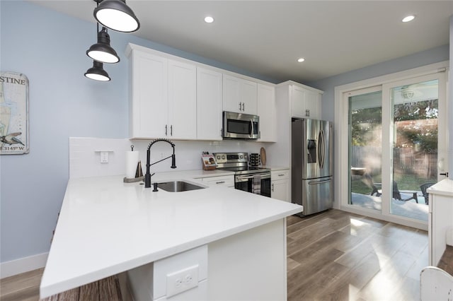 kitchen featuring kitchen peninsula, appliances with stainless steel finishes, sink, white cabinets, and plenty of natural light