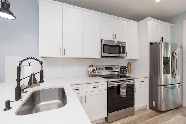 kitchen with white cabinets, light wood-type flooring, sink, and appliances with stainless steel finishes