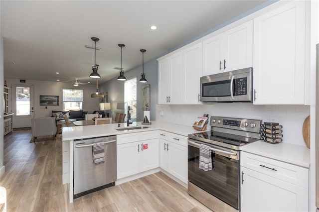 kitchen with sink, white cabinets, hanging light fixtures, and appliances with stainless steel finishes