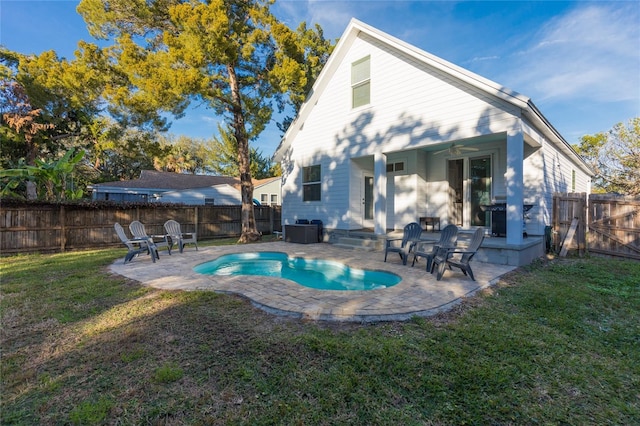 back of property featuring a lawn, ceiling fan, a fenced in pool, and a patio