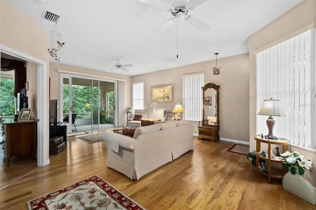 living room featuring ceiling fan with notable chandelier and light hardwood / wood-style floors