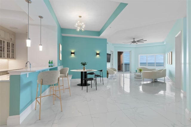 dining space featuring sink and ceiling fan with notable chandelier