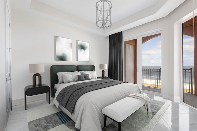 bedroom with a tray ceiling, access to exterior, a water view, and a notable chandelier