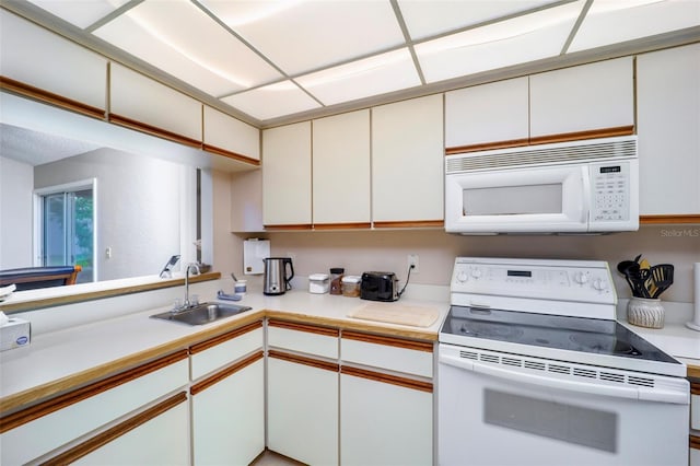 kitchen featuring white cabinets, kitchen peninsula, white appliances, and sink