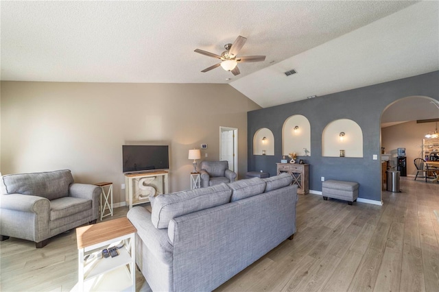 living room with ceiling fan, light hardwood / wood-style floors, a textured ceiling, and vaulted ceiling