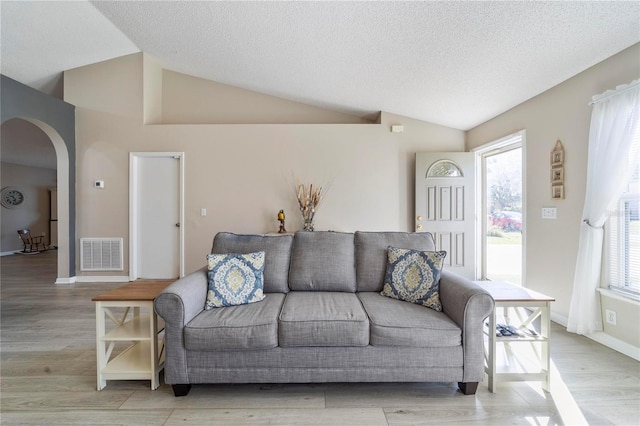 living room with light hardwood / wood-style floors, a textured ceiling, and vaulted ceiling