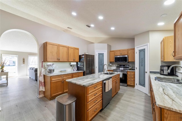 kitchen with sink, stainless steel appliances, a center island with sink, and light hardwood / wood-style flooring